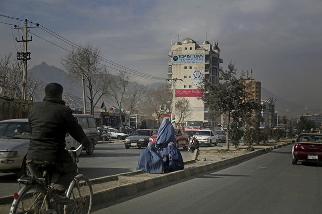 Afghan women sit on a road divider as they seek alms from pedestrians outside a camp for internally displaced people in Kabul, Afghanistan, Monday, Dec. 9, 2019. [Photo: AP/Altaf Qadri]