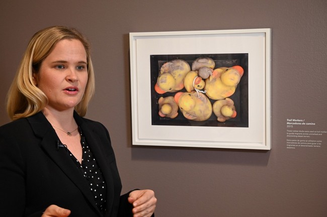 Curator Laura Mart stands beside a photo called "Trail Markers" showing rubber ducks that were confiscated from migrants who used them to indicate routes through the desert as they walked from Mexico to the U.S. at the exhibition "Sueno Americano / The American Dream: Photographs by Tom Kiefer" at the Skirball Cultural Center in Los Angeles, on December 10, 2019. [Photo: AFP]