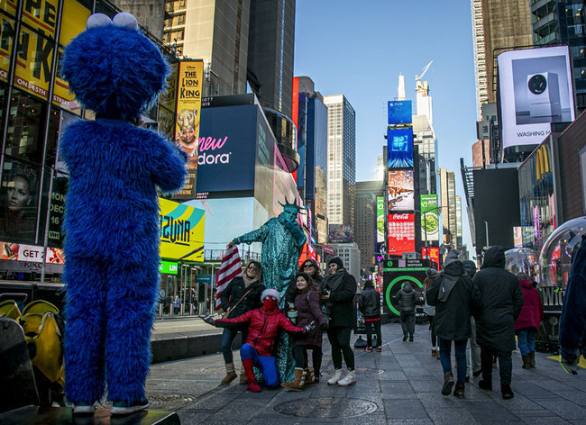 In this Thursday, Dec. 19, 2019 photo, people snap pictures with familiar costumed characters, who solicit money to perform for the photos in Times Square in New York. Complaints about the sometimes aggressive behavior of the performers prompted the city in 2016 to passed a law relegating the Times Square characters to 8-by-50 foot “activity zones" where they might annoy fewer people. [Photo: AP/Bebeto Matthews]