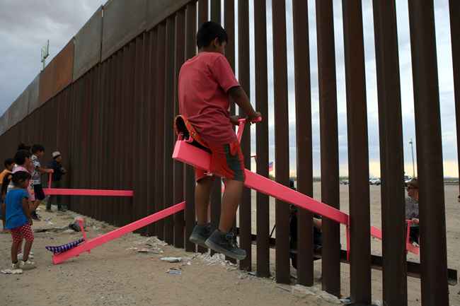 American and Mexican families play with a toy called "up and down" (Seesaw swing) over the Mexican border with US at the Anapra zone in Ciudad Juarez, Chihuahua State, Mexico on July 28, 2019. [Photo: LUIS TORRES/AFP]