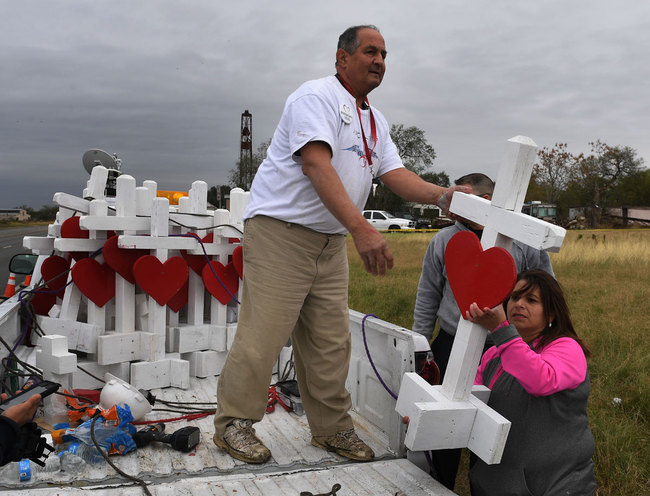 Carpenter Greg Zanis (C) who drove from Chicago unloads his crosses outside the First Baptist Church which was the scene of the mass shooting that killed 26 people in Sutherland Springs, Texas on November 8, 2017. [Photo: AFP]