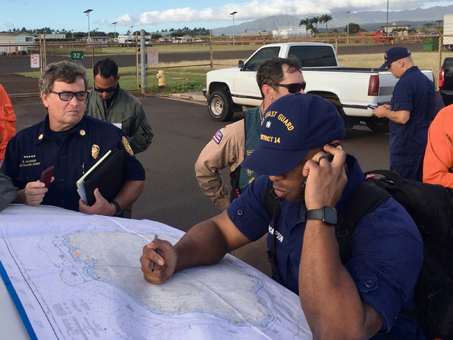 In this photo released by the U.S. Coast Guard, Coast Guard Incident Command Post responders look over a map of the Na Pali Coast State Wilderness Park on the Hawaiian island of Kauai on December 27, 2019, the day after a tour helicopter disappeared with seven people aboard. [Photo: AP]