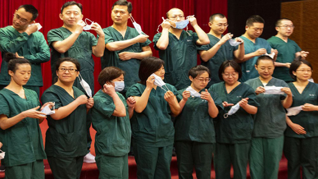 Snímek: Šestý lékařský tým z autonomní oblasti Vnitřní Mongolsko pořizuje skupinovou fotografii během svého pobytu v Respiračním výzkumném ústavu v nemocnici Union ve Wuhanu ve střední čínské provincii Hubei; 12. března 2020. / Duan Wei