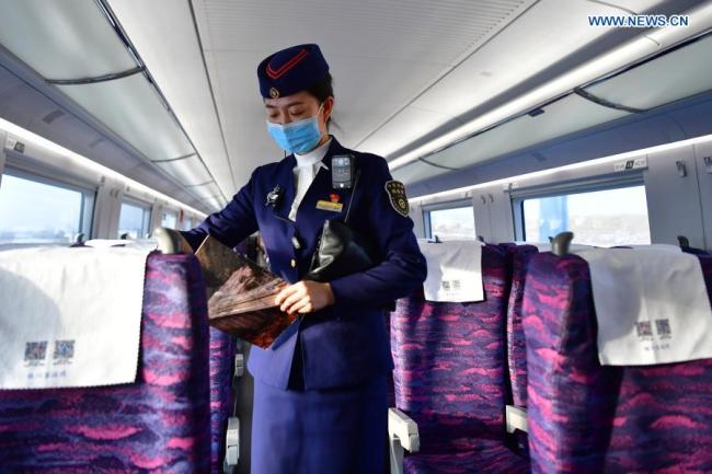 Šéfka průvodčích Dong Fang (Tung Fang) hlídkuje ve vysokorychlostním vlaku během zkušebního provozu vysokorychlostní železnice Yinchuan (Jin-čchuan) - Xi'an (Si-an) 12. prosince 2020. Vysokorychlostní železnice Yinchuan-Xi'an má být uvedena do provozu. (Xinhua / Chen Bin)
