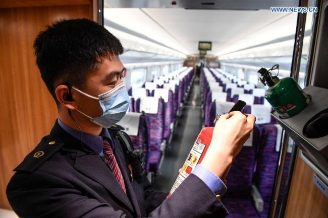 Člen vlakové posádky Zhang Long (Čang Lung) kontroluje hasicí přístroje na vysokorychlostním vlaku během zkušebního provozu vysokorychlostní železnice Yinchuan (Jin-čchuan) - Xi'an (Si-an) 12. prosince 2020. Vysokorychlostní železnice Yinchuan-Xi'an se chystá být uvedena do provozu. (Xinhua / Feng Kaihua)