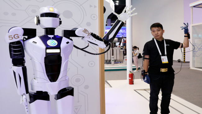Snímek: Zaměstnanec předvádí dálkové ovládání robota na bázi 5G během Světové konference o umělé inteligenci 2019 v čínské Šanghaji; 29. srpna 2019. / Xinhua