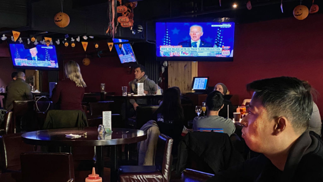 Zákazníci sledují projev Joe Bidena v televizi během akce sledující volby v místním baru v čínském Pekingu, 4. listopadu 2020. / Getty