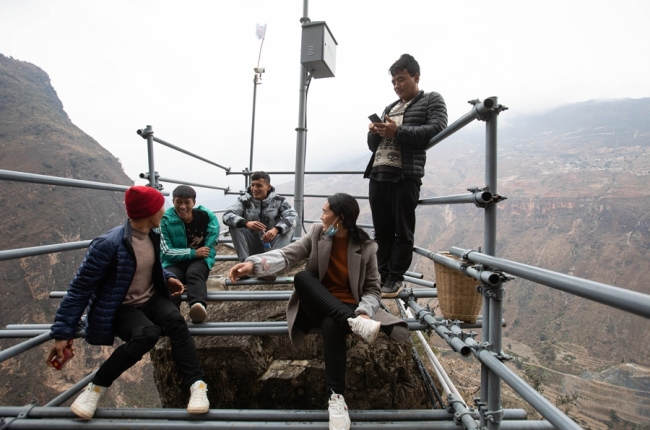 Mose (uprostřed) spočívá na ocelovém žebříku se svými společníky. Stavební materiály pro ubytování v rodině musí být přepraveny do vesnice po ocelovém žebříku. [Photo / Xinhua]