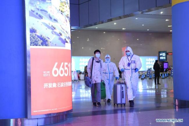 Dobrovolný řidič Fan Yuejia (Fan Jüe-ťia, R) doprovází vracejícího se cestujícího z nádraží Shijiazhuang (Š'-ťia-čuang) na bezplatnou jízdu během pandemie COVID-19 v Shijiazhuangu v provincii Hebei (Che-pej) v severní Číně 18. ledna 2021. Vzhledem k tomu, že všechny ostatní služby veřejné dopravy v Shijiazhuangu byly pozastaveny z důvodu prevence a kontroly COVID-19, místní řidiči se nabídli s dobrovolnou pomocí. 800členný tým dobrovolných řidičů, který vede 36letý Fan Yuejia, poskytuje cestujícím, kteří přijedou do tohoto města před čínským lunárním novým rokem, bezplatné jízdy. (Xinhua / Zhu Xudong)