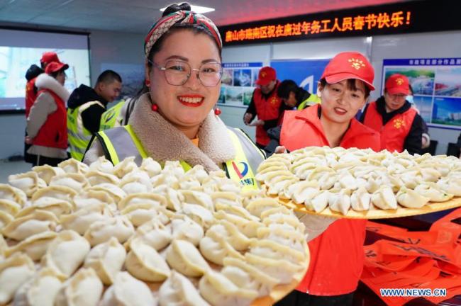 Dobrovolníci a zaměstnanci stavebního projektu ukazují taštičky, které vyrobili ve městě Tangshan (Tchang-šan) v severočínské provincii Hebei (Che-pej), 11. února 2021. Letošní Jarní svátek připadá na pátek. (Xinhua)