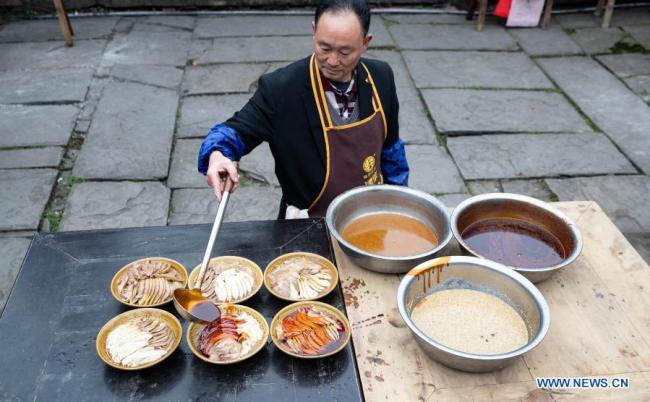 Kuchař vyrábí „Bang Bang Ji (Pang Pang Ťi)“, místní kuřecí svačinu, před lunárním Novým rokem v okrese Yingjing (Jing-ťing) v provincii Sichuan (S'-čchuan) v jihozápadní Číně, 4. února 2021. Lunární Nový rok patří k nejvýznamnějším svátkům v Číně a oslavné činnosti jsou rozmanité, včetně jídla. Když přichází lunární Nový rok, lidé po celé Číně připravují různá občerstvení, která, jak věří, jim přinesou štěstí. (Xinhua / Liu Mengqi)