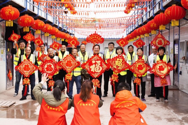 Dobrovolníci fotografují pracovníky, kteří zůstali na místě, kde pracují, na čínský Nový rok v Chongqingu (Čchung-čching) v jihozápadní Číně, 10. února 2021. (Xinhua / Qin Tingfu)