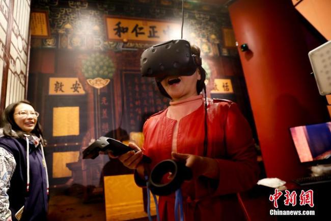 Une visiteuse découvre le palais Yangxin au Musée du Palais (autre nom de la Cité Interdite) à Beijing, avec l'aide de la technologie de réalité virtuelle (VR), le 10 octobre 2017. A l’occasion de son 92e anniversaire, le Musée vient d’ouvrir un centre numérique pour permettre aux visiteurs de découvrir encore davantage l'histoire et la culture du palais impérial. 