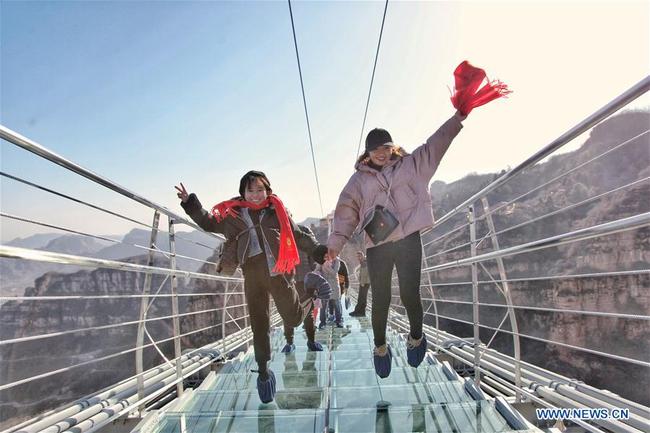 Des touristes marchent sur un pont suspendu en verre dans le site touristique de Hongyagu à Pingshan, district de la province chinoise du Hebei (nord), le 24 décembre 2017. Le pont suspendu en verre, d'une longueur de 488 mètres, a officiellement ouvert au public dimanche. (Xinhua/Liu Peiran)