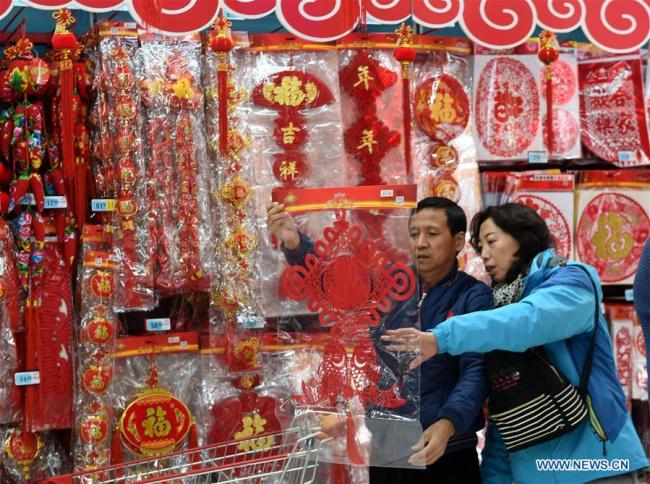 Des personnes sélectionnent des articles de décoration pour la Fête du printemps, dans la ville de Qingdao, dans la province du Shandong (est), le 14 janvier 2018. La Fête du printemps, ou Nouvel An lunaire chinois, tombera cette année le 16 février. (Phto : Li Ziheng)