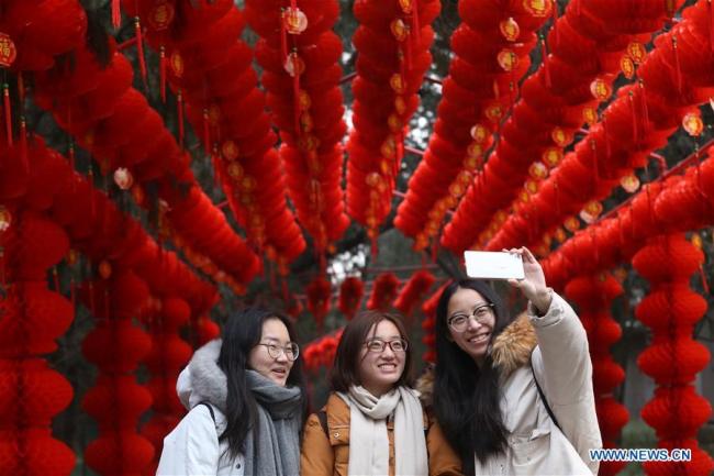 Des visiteuses prennent des selfies dans le couloir des lanternes du parc Ditan, également connu sous le nom de parc du Temple de la Terre, le 27 janvier 2018 à Beijing. (Photo / Xinhua)