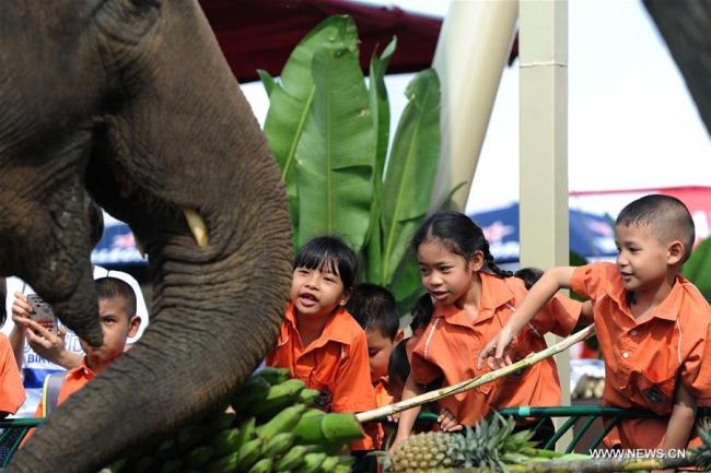 Des enfants donnent à manger à un éléphant avant un match de polo lors de la 16e Coupe du Roi, tournoi annuel de polo à dos d'éléphant, le 8 mars 2018 à Bangkok, en Thaïlande. (Photo : Rachen Sageamsak)