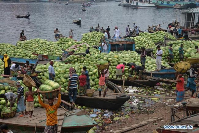 Des ouvriers déchargent des pastèques des bateaux près d'un marché à Dhaka, capitale du Bangladesh, le 21 avril 2018.