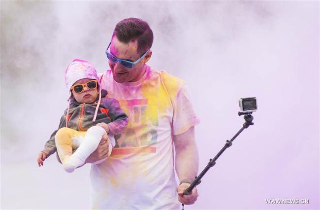 Un père prend un selfie avec son bébé lors d'une course en couleurs à Toronto au Canada, le 12 mai 2018. (Xinhua/Zou Zheng)