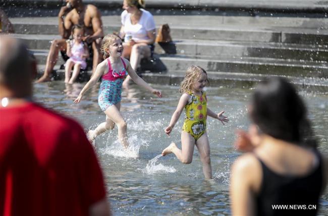  De jeunes filles s'amusent dans une fontaine à New York aux Etats-Unis, le 2 juillet 2018. La température a atteint jusqu'à 35 degrés lundi dans la ville américaine. (Photo : Wang Ying)