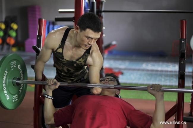  Ni Mincheng conseille un amateur dans sa salle de gym à Jinhua, dans la province chinoise du Zhejiang, le 2 juillet 2018. Ni Mincheng a perdu ses bras quand il était petit. Il est ensuite devenu athlète. Maintenant il dirige sa propre salle de gym. (Photo : Ge Yuejin)