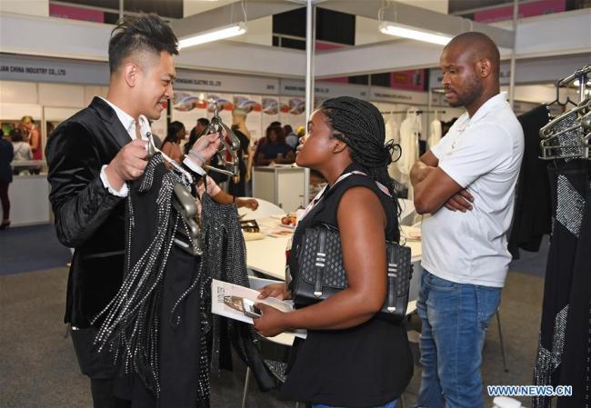 Un exposant présente des vêtements à des visiteurs lors du Salon "China Homelife & China Machinex 2018" à Johannesburg, en Afrique du Sud, le 26 septembre 2018. Le salon a ouvert ses portes mercredi à Johannesburg, avec plus de 600 sociétés chinoises recherchant des partenaires commerciaux dans les pays d'Afrique. (Photo : Chen Cheng)
