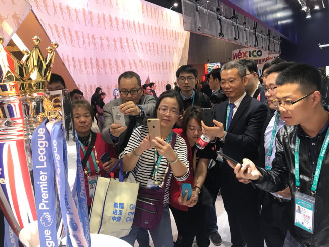 Des visiteurs prennent des photos du trophée de la Premier League anglaise au pavillon du Royaume-Uni lors de la toute première Foire internationale des importations de Chine, le 6 novembre 2018 à Shanghai. 
