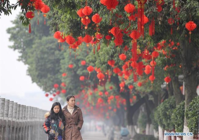 Des gens passent devant des décorations rouges sur une route du comté de Daoxian, à Yongzhou, dans la province du Hunan (centre de la Chine), le 26 janvier 2019.