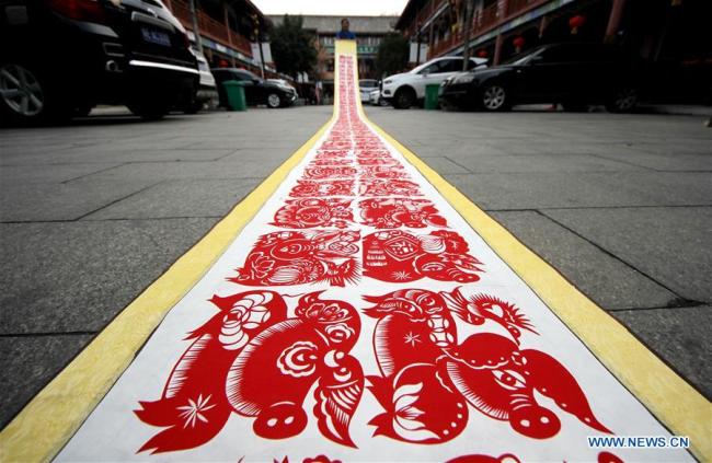 L'artiste folklorique Shi Hongxia crée une œuvre d'art en papier découpé sur le thème du cochon à Tengzhou, ville de la province chinoise du Shandong (est), le 31 janvier 2019. M. Shi a mis deux mois à créer cette œuvre d'art de neuf mètres de long comportant 100 figures de cochon pour accueillir la prochaine année du cochon. (Xinhua/Sun Zhongzhe)