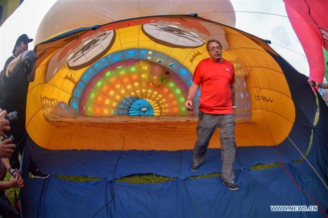 Des gens visitent le Festival des montgolfières à Penang, en Malaisie, le 10 février 2019. De nombreuses montgolfières manipulées par des aérostiers internationaux et locaux sont exposées durant ce festival de deux jours qui s'est ouvert samedi. (Photo : Chong Voon Chung)
