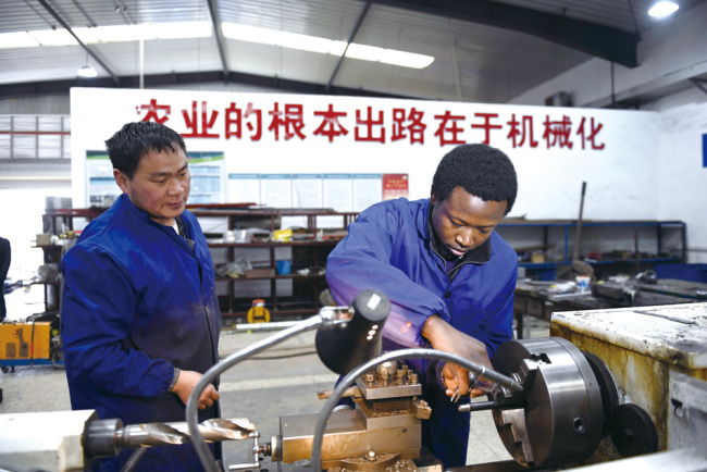 Photo à droite: Chu Ke (à droite) apprend de son enseignant, Chen Changguang, comment utiliser des machines dans un centre de formation de l'Université d'agriculture du Hunan, 14 mars 2019. (Photo crédit : Xinhua / Li Ga)