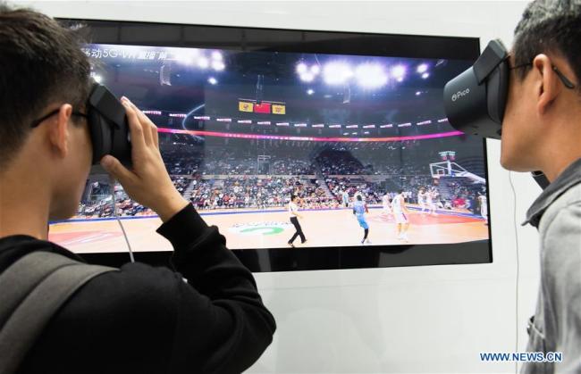 Des visiteurs regardent la retransmission en direct d'un match de basket-ball via des dispositifs de réalité virtuelle et 5G au centre d'exposition « Lumière de l’Internet » à Wuzhen, dans la province du Zhejiang (est de la Chine), le 19 octobre 2019.