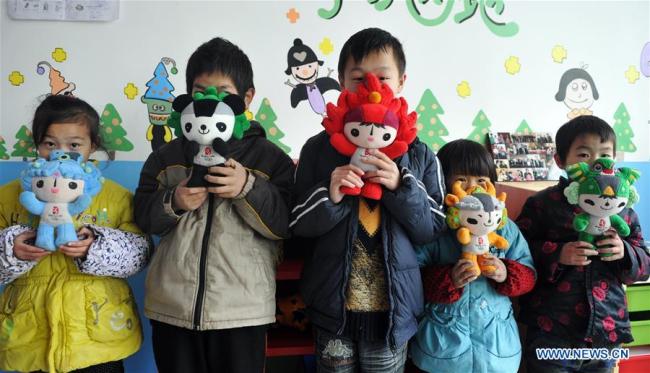 Junjun (au centre) et d'autres enfants rendus orphelins par le VIH/sida présentent les mascottes des Jeux olympiques de 2018 à Fuyang, dans la province de l'Anhui (est de la Chine), le 30 novembre 2011. (Photo / Xinhua)