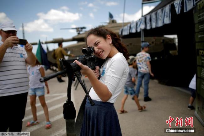 Le 8 mai, en Israël, une fille lève un fusil pour jouer lors d'une cérémonie commémorant des soldats décédés. Photo prise par Corinna Kern.