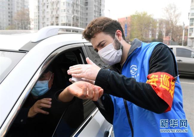 Photo prise le 31 mars, montrant Lu Shangyi prenant la température des habitants à l’entrée d’une communauté de Beijing. (Photos : Ren Chao/Xinhua)
