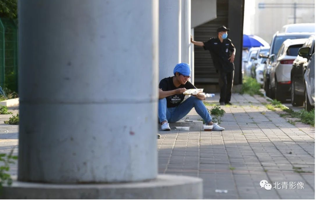 Un travailleur mange près de la rue quand les autres prennent le relai.<br>