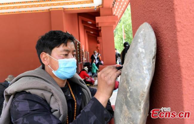 Ένας τεχνίτης χαράζει μια πέτρα σε ένα πάρκο πετρογλυφικών στο Μπανγκτουό, κομητεία Ρανγκτανγκ του Αυτόνομου Νομού Θιβετιανών Νγκάγουα (Άμπα) και Τσιανγκ στην επαρχία Σιτσουάν της νοτιοδυτικής Κίνας, στις 13 Ιουνίου 2020.<br><br> <br><br>Το πάρκο πετρογλυφικών ιδρύθηκε το 2017, και διατηρεί κειμήλια με ιστορική αξία, όπως η λαμαϊστική παγόδα και οι βουδιστικές πέτρες με χαραγμένα σούτρα. (Φωτογραφία: China News Service / An Yuan)