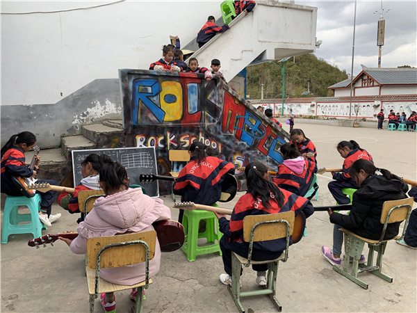 Οι μαθητές στο Δημοτικό Σχολείο Χάιγκα στο Λιουπανσούι, επαρχία Γκουιτζόου, παρακολουθούν ένα υπαίθριο μάθημα μουσικής κατά τη διάρκεια του μεσημεριανού διαλείμματος. [Η φωτογραφία παρέχεται στην China Daily)