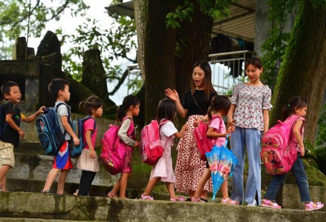 Η Γουέι Τσουνλάν, δασκάλα από το κεντρικό σχολείο στο νομό Rongsui, χαιρετά τους μαθητές της στο σχολείο Γουγίνγκ την 1η Ιουλίου. Έχει ανατεθεί στους δάσκαλους από το Γκαντόνγκ να εργάζονται τακτικά στο Γουγίνγκ.