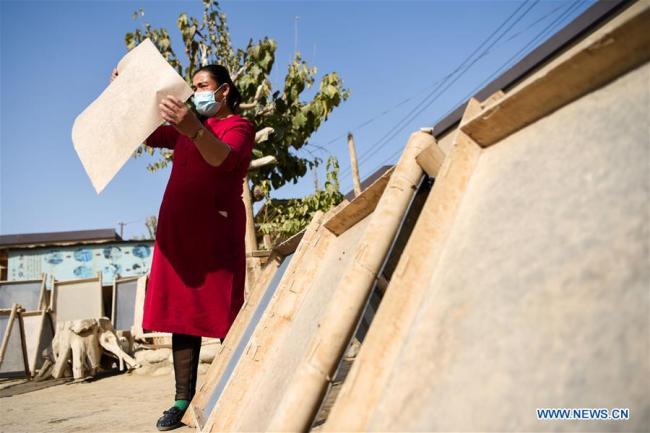 Τεχνίτρια ελέγχει στον ήλιο ένα κομμάτι χαρτί που έγινε από φλοιό μουριάς στην κομητεία Μογιού του Χοτάν, στην Αυτόνομη Περιοχή Σιντζιάνγκ Ουιγκούρ της βορειοδυτικής Κίνας, την 1η Νοεμβρίου 2020. 