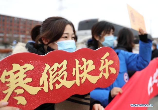 Εργαζόμενοι του πανεπιστημίου χαιρετούν τους φοιτητές που ανεβαίνουν στο πούλμαν που μίσθωσε το Πανεπιστήμιο Τεχνολογίας του Νταλιάν, στην επαρχία Λιαονίνγκ της βορειοανατολικής Κίνας στις 20 Ιανουαρίου 2021. 