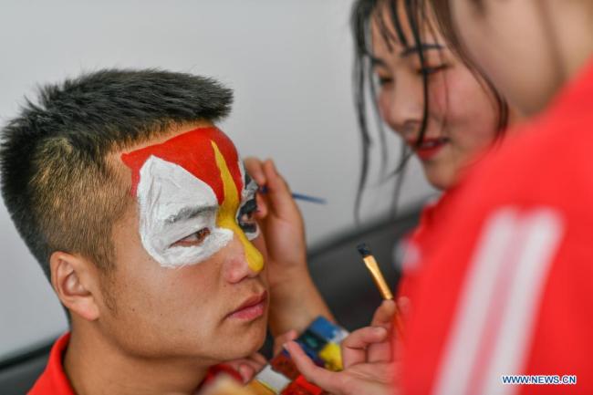 Μαθητές μακιγιάρονται πριν από την πρόβα για την όπερα Ταϊπίνγκ Χουαντενγκσί στο 3ο Γυμνάσιο της κομητείας Λονγκλί, στον Αυτόνομο Νομό Τσιενάν Μπουγί και Μιάο που βρισκεται στην νοτιοδυτική Κίνα στις 23 Μαρτίου 2021. <br>