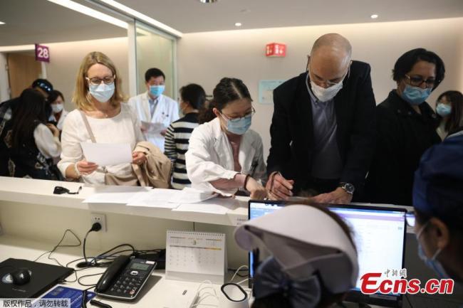 Αλλοδαποί κάτοικοι της Σαγκάης περιμένουν στην σειρά για να υπογράψουν μια ενημερωτική επιστολή συναίνεσης πριν από τον εμβολιασμό εμβολίου COVID-19 στη Σαγκάη, στις 29 Μαρτίου 2021. (Φωτογραφία: China News Service)