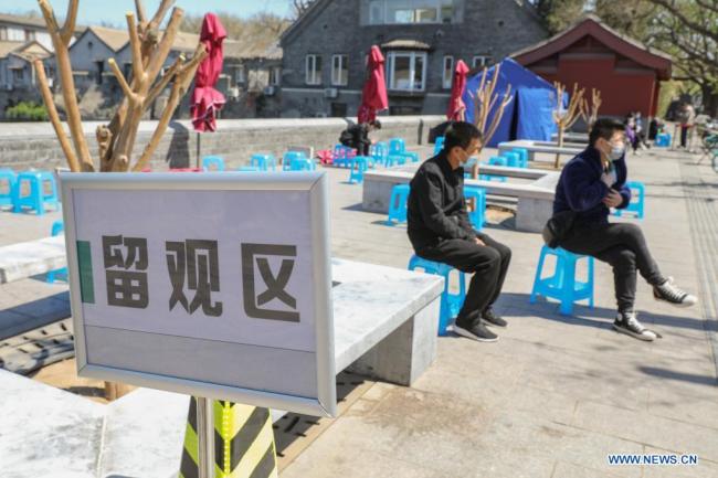 Οι άνθρωποι παραμένουν σε μια περιοχή παρατήρησης μετά τη λήψη των εμβολίων COVID-19 σε ένα όχημα κινητού εμβολιασμού έξω από την Απαγορευμένη Πόλη στο Πεκίνο, πρωτεύουσα της Κίνας, στις 13 Απριλίου 2021. (φωτογραφία / Xinhua)