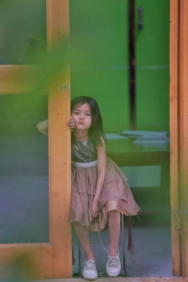 3. Ένα κορίτσι κάθεται μπροστά από το σπίτι της στον πεζόδρομο Τουαντσένγκ στην πόλη Χοτάν, στην αυτόνομη περιοχή Σιντζιάνγκ Ουιγκούρ της βορειοδυτικής Κίνας, 22 Μαΐου 2021.