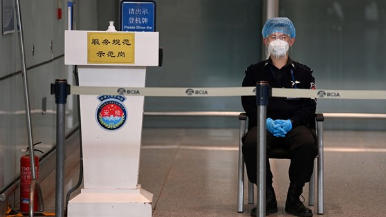 një rojë e sigurimit shikon mbi kanelin bosh të arritjes ndërkombëtare në aeroportin e Pekinit.
