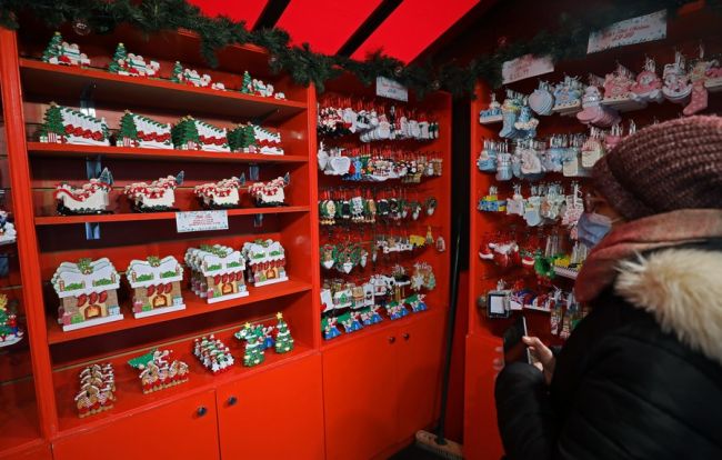 Foto: Një grua po shikon stolisjet e Krishtlindjeve të prodhuara në Kinë në një treg në sheshin “Trafalgar” në Londër të Britanisë, 23 dhjetor 2021 (Foto:Xinhua)