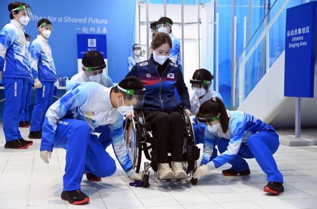 Vullnetarët pastruan karrocën për një paralimpiste gjatë konkurrimit të kerlingut me karrocë të Lojërave Paralimpike Dimërore të Pekinit 2022/ Xinhua