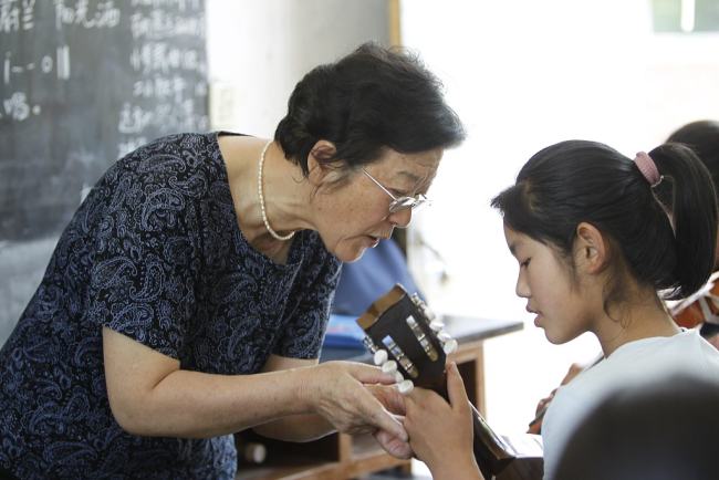 Deng Xiaolan e mësoi një vajzë në luajtjes së kitarës, më 19 qershor 2011/ VCG