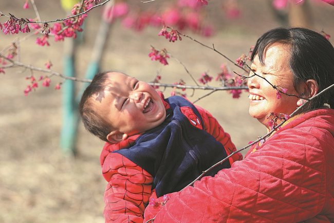 Një gjyshe dhe nipi i saj luajtën në një kopsht në Changde të provincës Hunan në pranverën e herët/ foto nga Chen Zide për "China Daily"